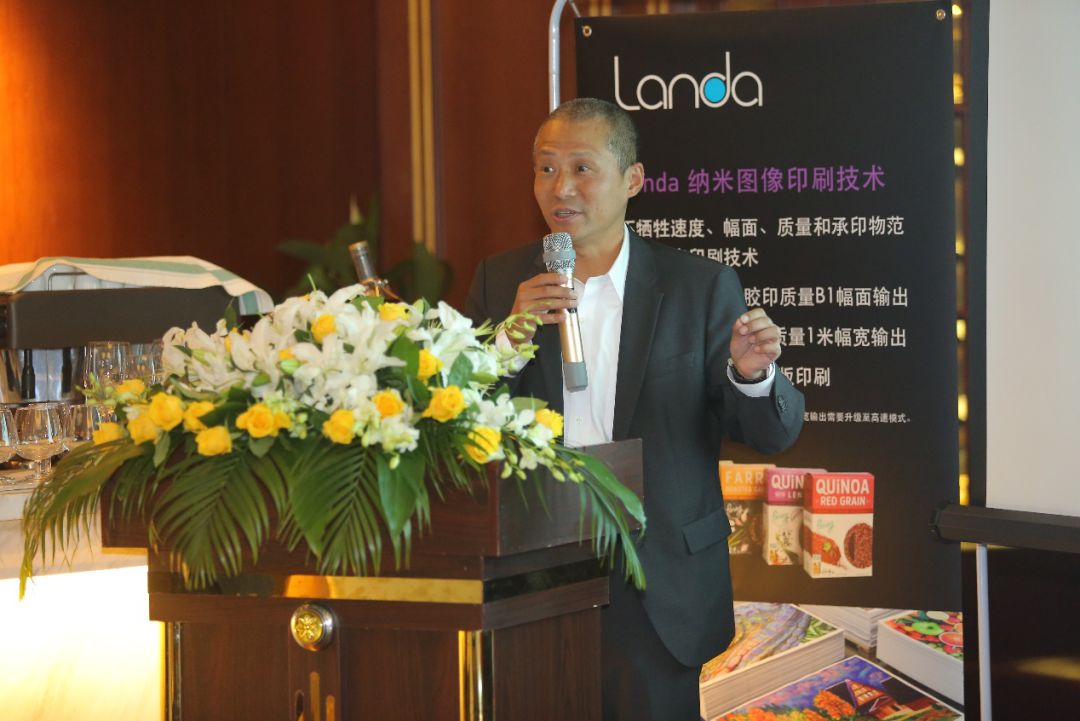 Landa标牌与花饰讲台旁手持麦克风的人