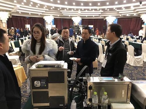 会议厅内多人在金属机柜及两瓶饮料旁