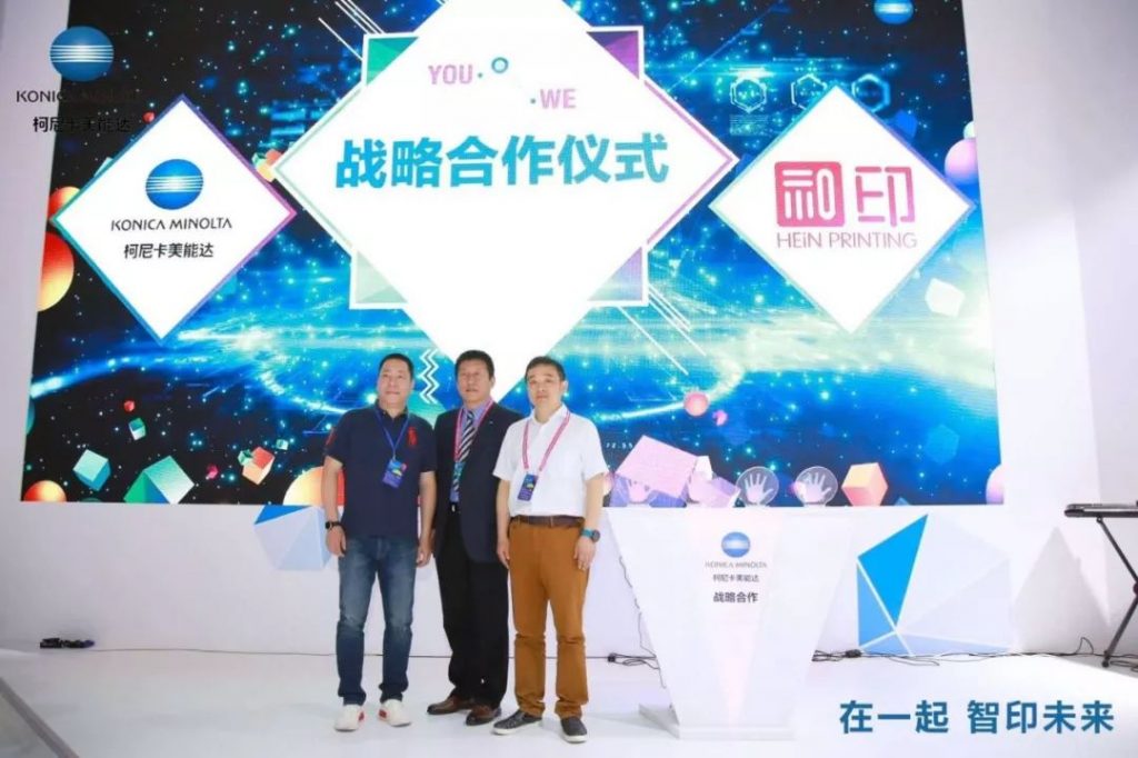 www.eamar_.com_.cn-news984123808-1024x682 三名男子在柯尼卡美能达与和印标志布景前合影