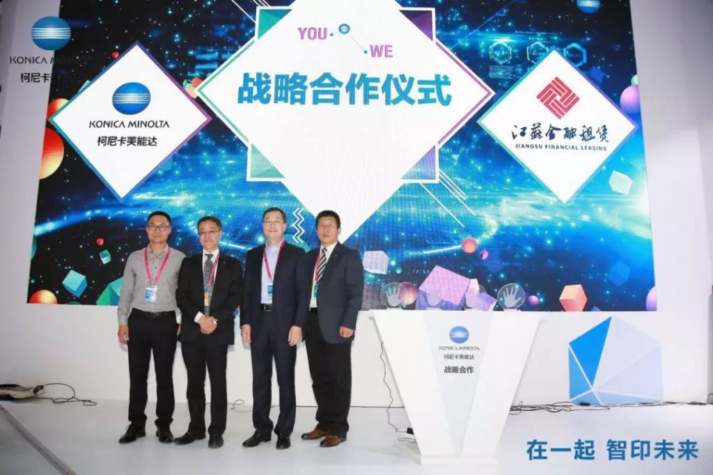 www.eamar_.com_.cn-news984123809-1024x682 四名男子在柯尼卡美能达与江苏金融租赁标志布景前合影