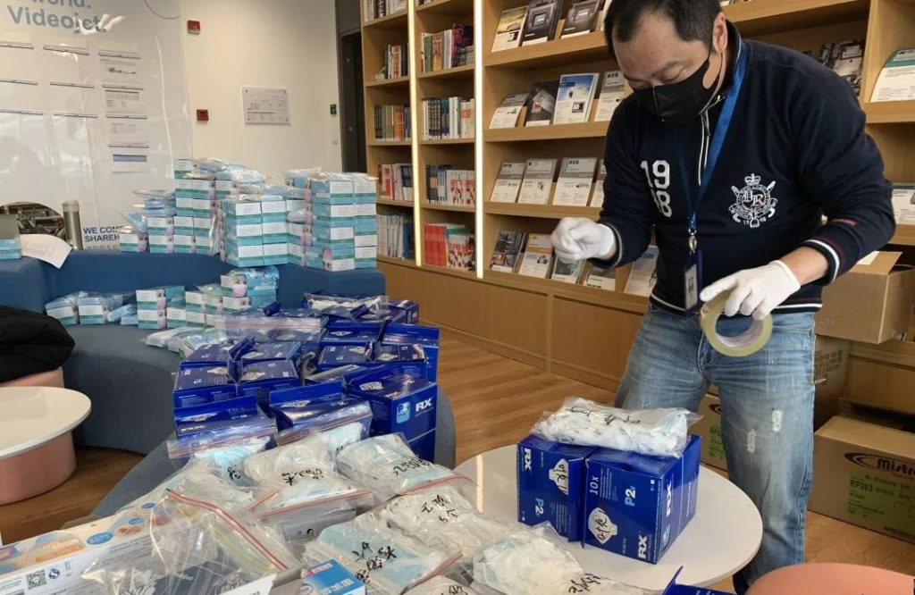戴口罩手套的人拿胶带整顿桌面包装