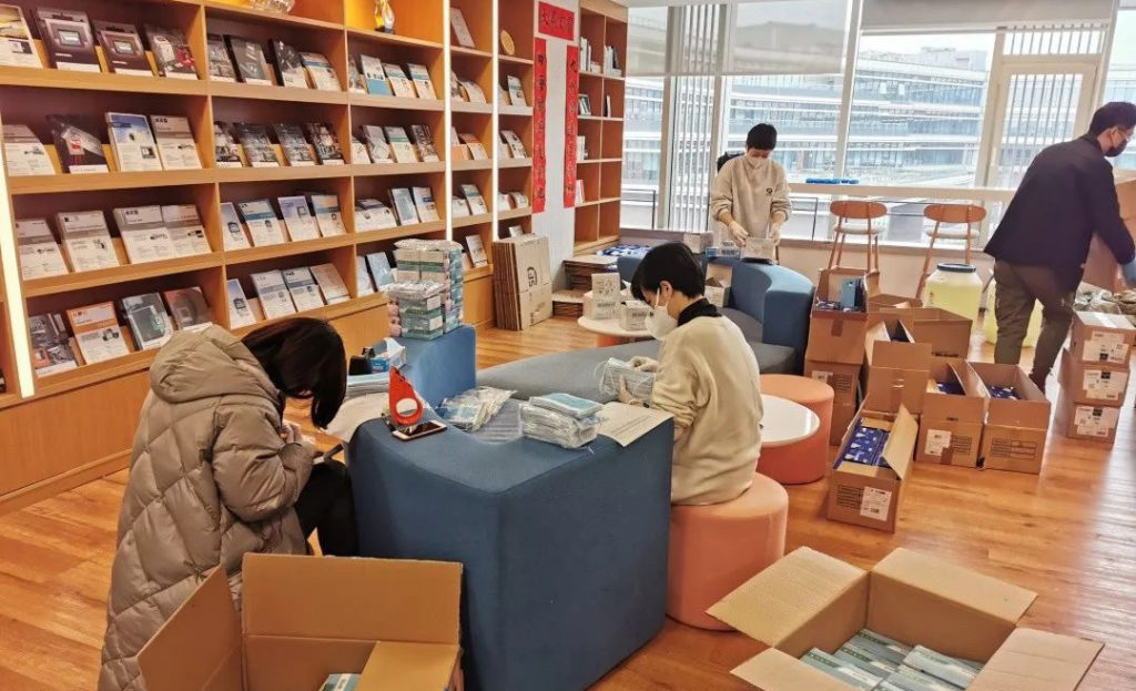 多人在摆有包装物和纸箱的室内桌边整顿物品