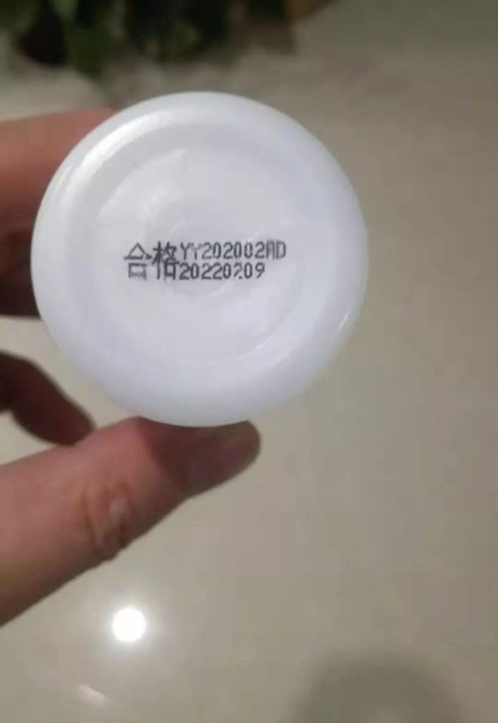 手持白色圆形物件上的合格字样及两行点阵编码