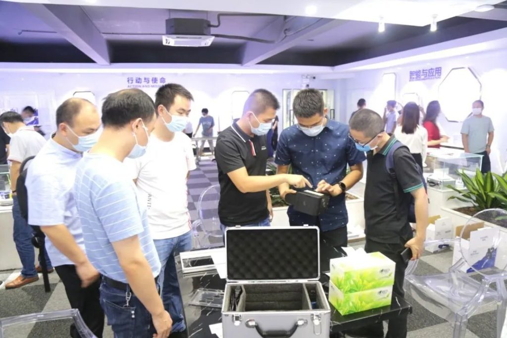 戴口罩的人群围看手持玄色设备