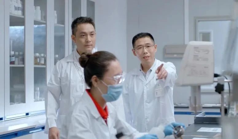 三名穿白大褂的人在尝试台旁查看仪器
